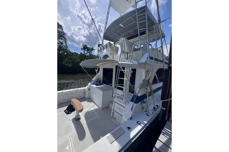 Slide: The Image of 1986 Bertram 46III Convertible yacht docked by a scenic river. - 6