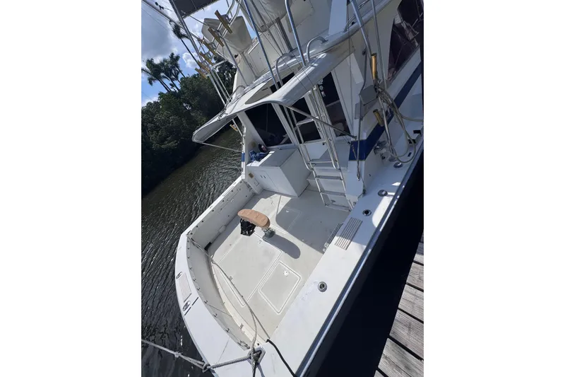 Slide: The Image of 1986 Bertram 46III Convertible yacht docked, showcasing spacious deck and fishing chair. - 5