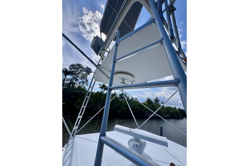 Slide: The Image of 1986 Bertram 46III Convertible boat tower with clear sky and lush greenery background. - 35