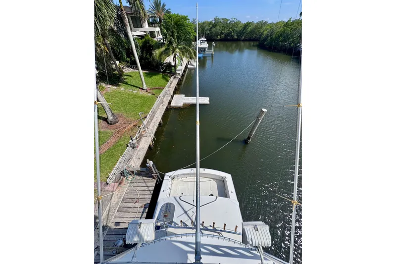 Slide: The Image of 1986 Bertram 46III Convertible yacht docked by a lush, tree-lined canal. - 42