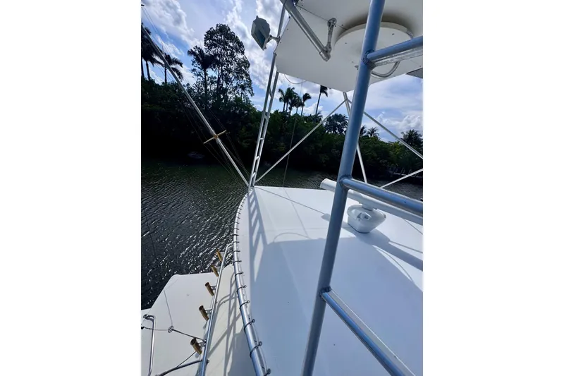 Slide: The Image of 1986 Bertram 46III Convertible yacht deck with railing, surrounded by lush greenery. - 36