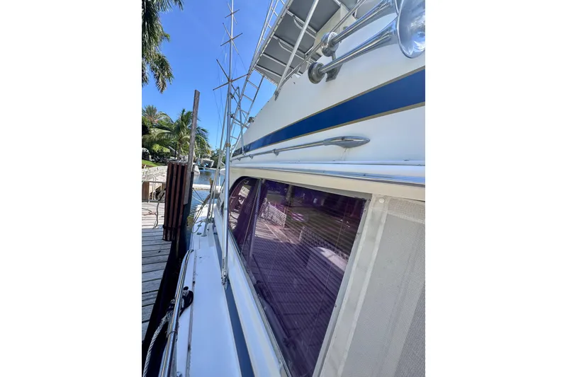 Slide: The Image of 1986 Bertram 46III Convertible yacht docked, showcasing sleek design and polished exterior. - 52
