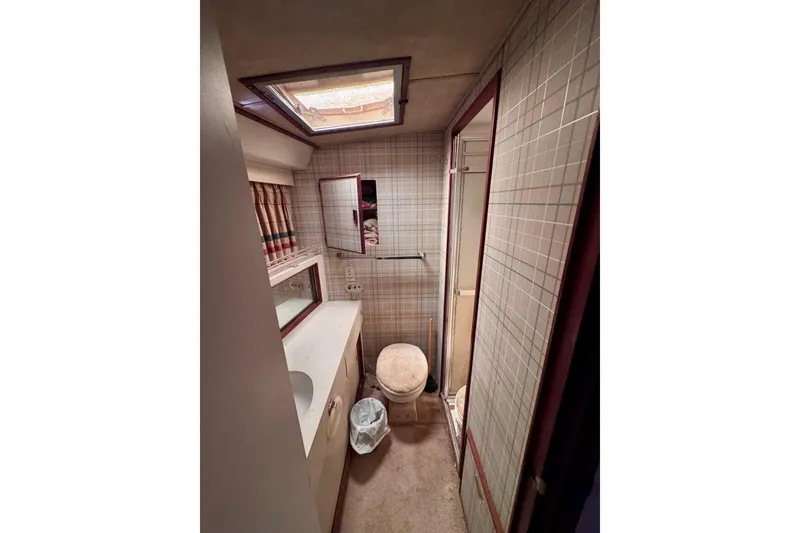 Slide: The Image of 1986 Bertram 46III Convertible yacht bathroom with tiled walls and skylight. - 58
