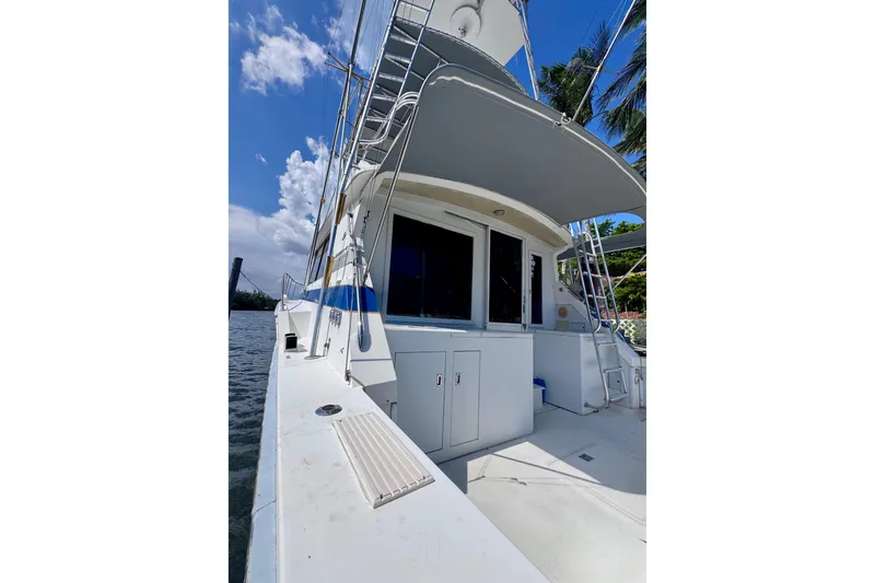 Slide: The Image of 1986 Bertram 46III Convertible yacht docked, showcasing sleek design and spacious deck under clear skies. - 9