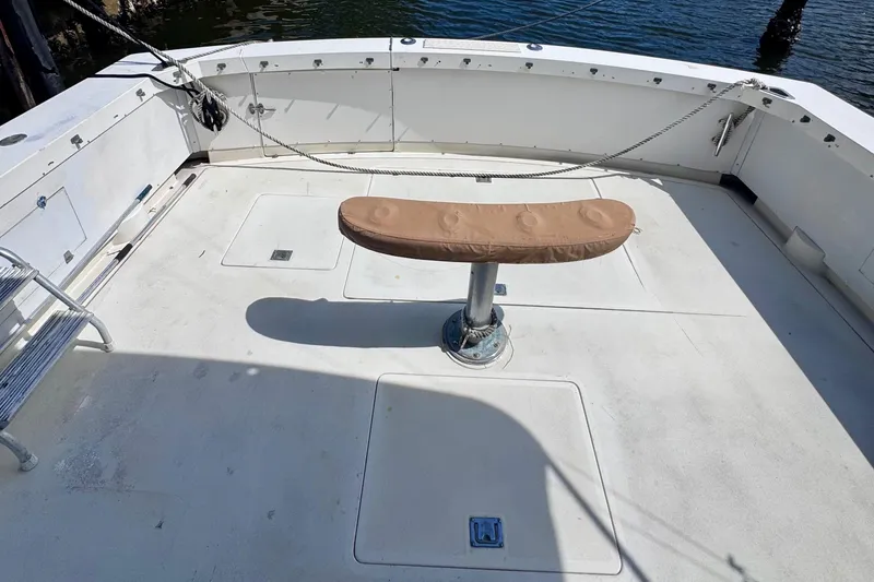 Slide: The Image of 1986 Bertram 46III Convertible boat deck with cushioned seat, docked by water. - 11