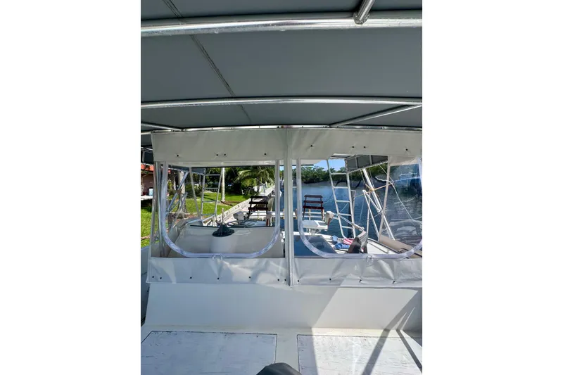 Slide: The Image of 1986 Bertram 46III Convertible boat interior with clear canopy and scenic waterway view. - 32