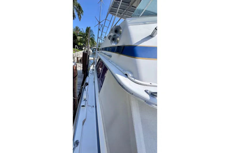 Slide: The Image of 1986 Bertram 46III Convertible yacht docked, showcasing sleek design and vibrant blue accents. - 51