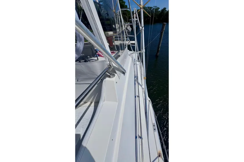 Slide: The Image of 1986 Bertram 46III Convertible yacht deck with railing, docked by calm water. - 31