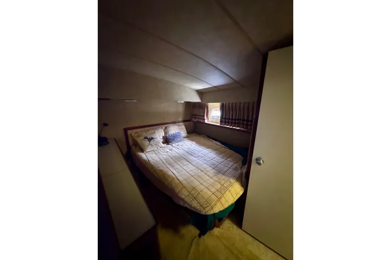 Slide: The Image of Cozy bedroom interior of 1986 Bertram 46III Convertible yacht with bed and window. - 57