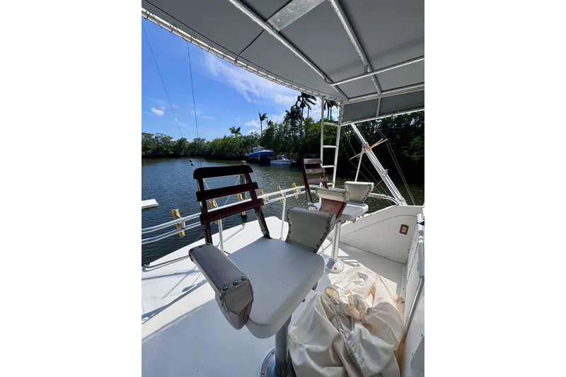 Slide: The Image of 1986 Bertram 46III Convertible boat deck with chairs, overlooking serene waterway. - 22