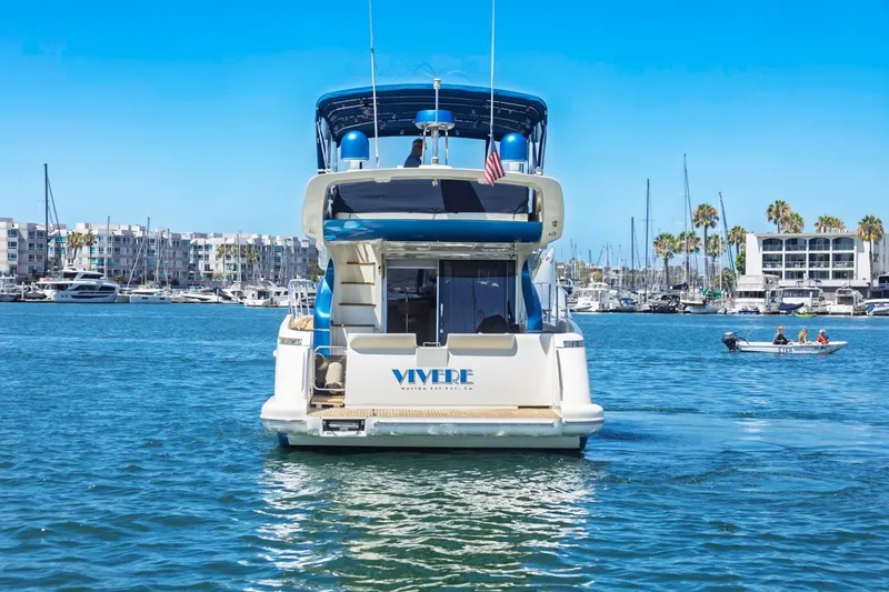 Slide: The Image of Azimut 43 yacht from 2006 on a sunny marina, with buildings and palm trees in the background. - 3
