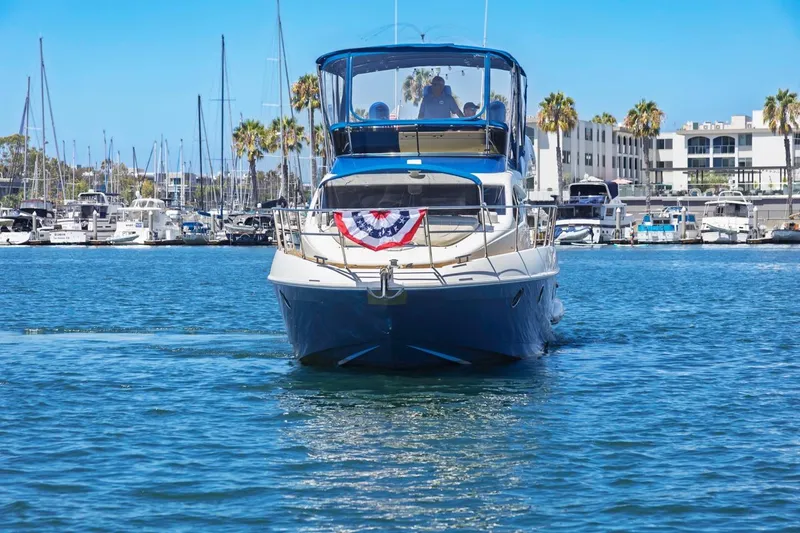 Slide: The Image of 2006 Azimut 43 yacht cruising in a marina with palm trees and buildings. - 2