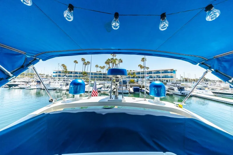 Slide: The Image of 2006 Azimut 43 yacht docked in marina, blue canopy, palm trees, and waterfront buildings. - 17