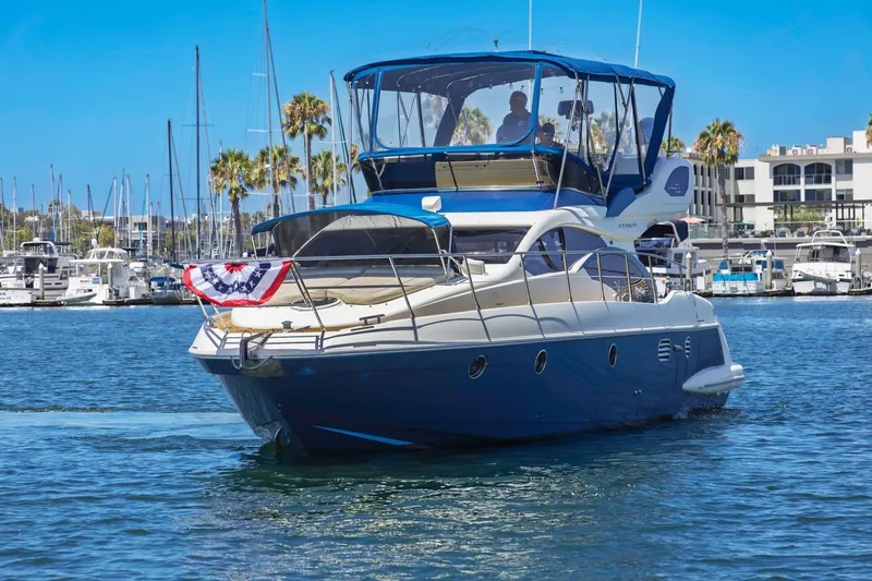 Slide: The Image of 2006 Azimut 43 yacht cruising in a marina with palm trees and boats. - 1