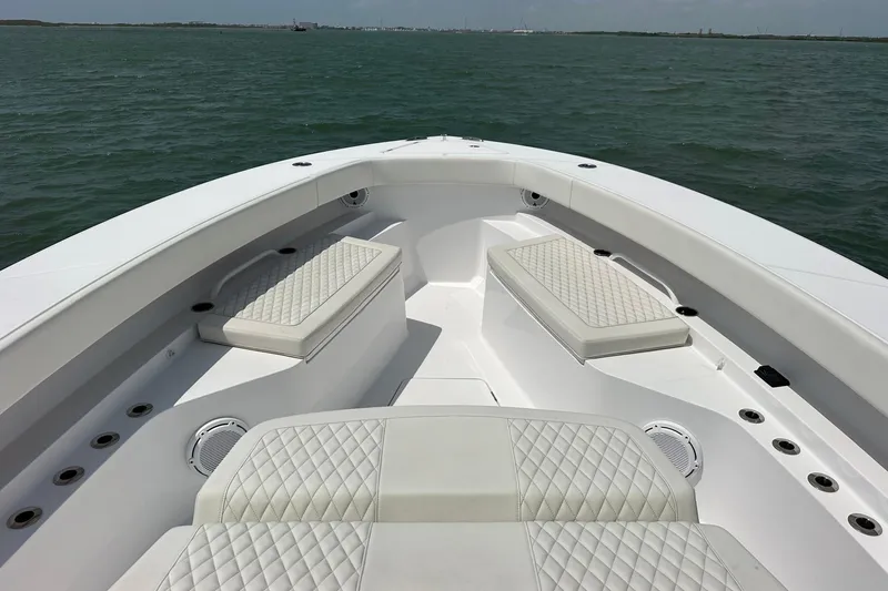 Slide: The Image of Bow seating area of 2023 Jupiter 43 boat with quilted cushions on open water. - 18