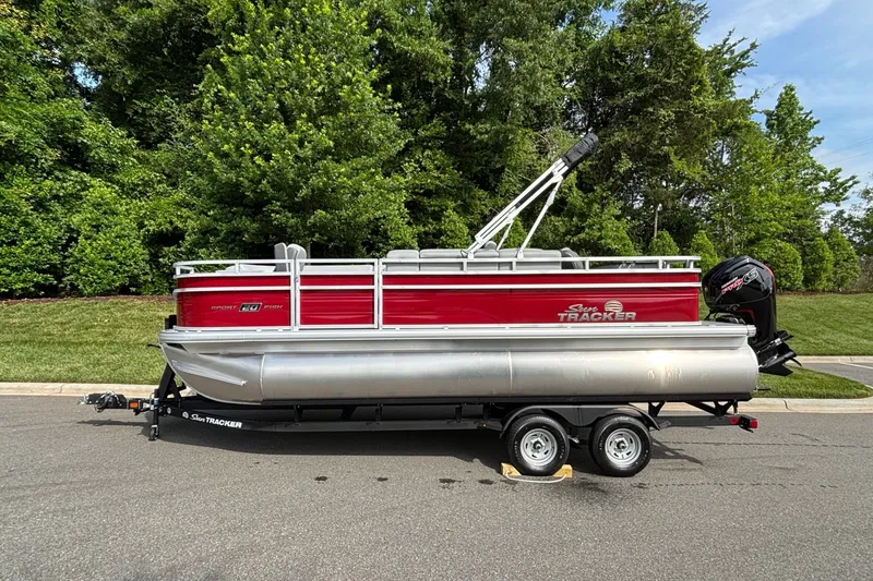 The Image of 2026 Sun Tracker SportFish 20 DLX pontoon boat on trailer, parked on a road. - 0