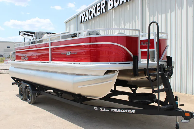 Slide: The Image of 2026 Sun Tracker Fishin' Barge 22 DLX pontoon boat on trailer, red and silver design. - 13