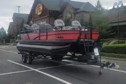Slide: The Image of 2026 Ranger 220F boat on trailer in parking lot, near rustic building. - 1