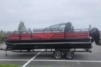 Slide: The Image of A red and black pontoon boat sits on a trailer in a parking lot. - 56