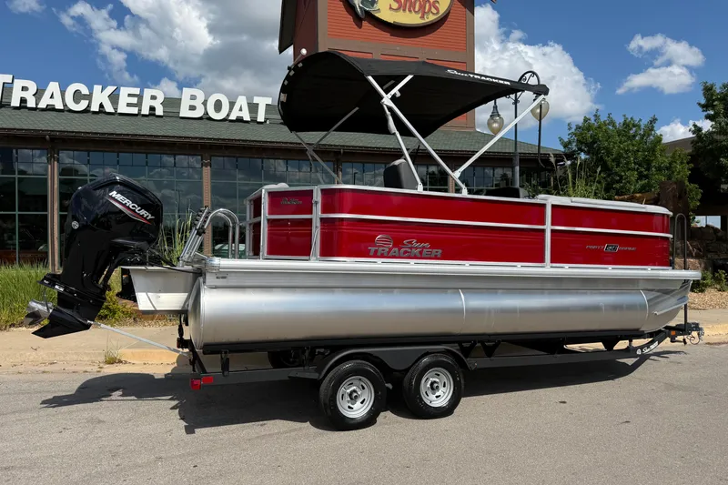 Slide: The Image of 2026 Sun Tracker Party Barge 20 DLX pontoon boat with Mercury engine, parked outside showroom. - 8