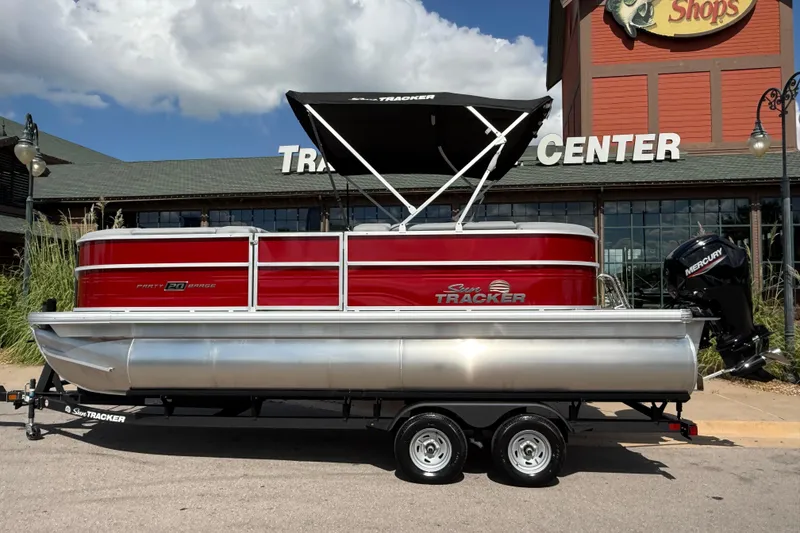 The Image of 2026 Sun Tracker Party Barge 20 DLX pontoon boat displayed outside a retail center. - 0