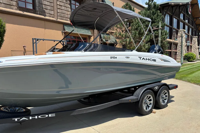 Slide: The Image of 2026 Tahoe 210 S boat on trailer, parked outdoors near a building. - 3