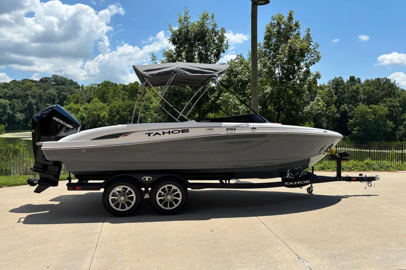 The Image of 2026 Tahoe 210 S boat on trailer, parked outdoors under a sunny sky. - 0