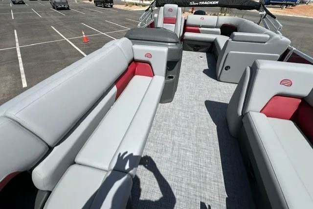Slide: The Image of 2026 Sun Tracker Party Barge 20 DLX interior with gray and red seating in a parking lot. - 14