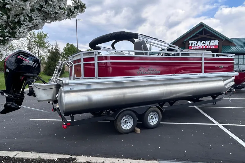 The Image of 2026 Sun Tracker Fishin' Barge 22 DLX pontoon boat on trailer in parking lot. - 0