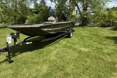 Slide: The Image of 2026 Tracker Grizzly 1860 CC boat on trailer, parked on grassy area with trees. - 2