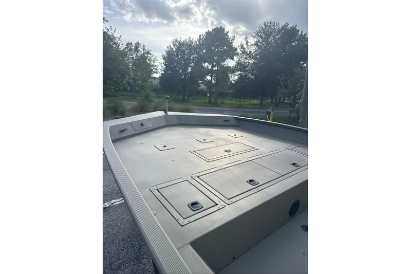 Slide: The Image of 2026 Tracker Grizzly 2072 CC boat deck with storage compartments, under a cloudy sky. - 4