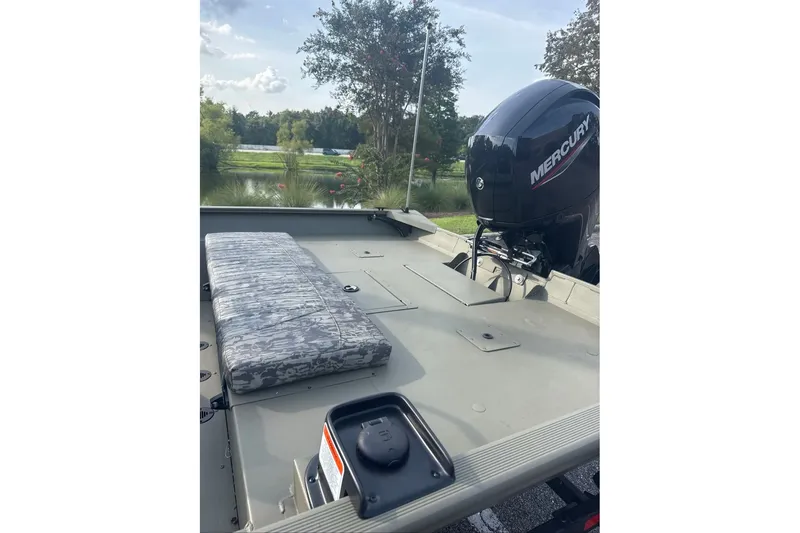 Slide: The Image of 2026 Tracker Grizzly 2072 CC boat with Mercury engine, docked near a scenic lake. - 6