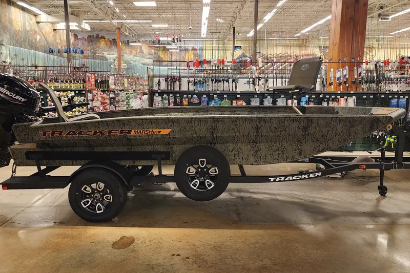 The Image of 2026 Tracker Grizzly 1756 T Marsh boat displayed in a store with fishing gear. - 0