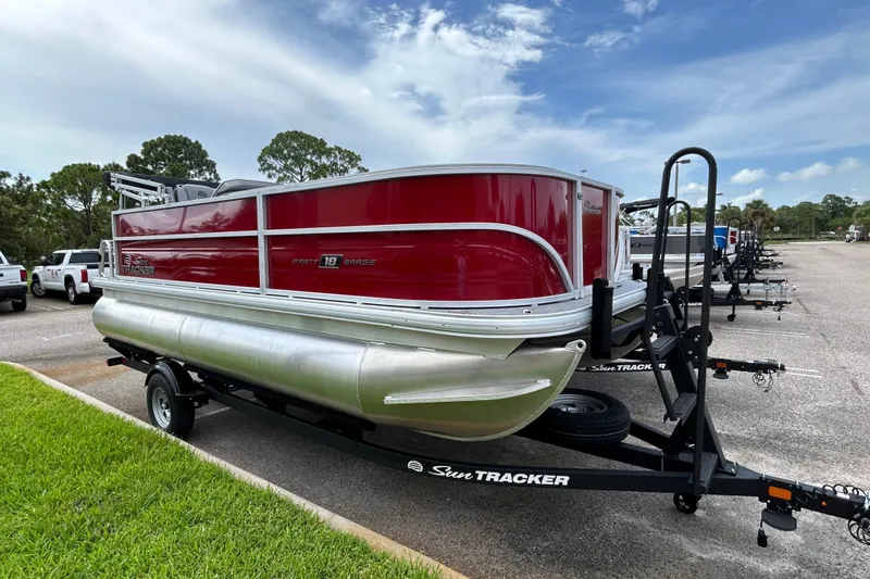 The Image of 2026 Sun Tracker Party Barge 18 DLX pontoon boat on trailer, parked outdoors. - 0
