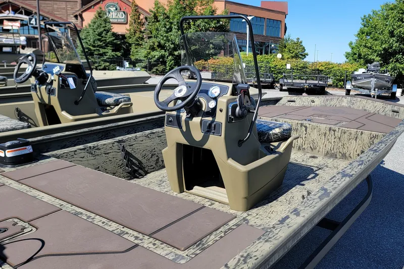 Slide: The Image of 2026 Tracker Grizzly 1860 CC boat with camouflage design, parked outdoors. - 2
