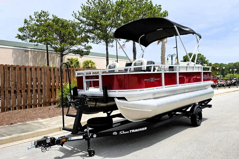Slide: The Image of 2026 Sun Tracker Bass Buggy 18 DLX pontoon boat on trailer, parked outdoors. - 10