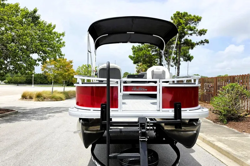 Slide: The Image of 2026 Sun Tracker Bass Buggy 18 DLX pontoon boat on trailer, parked outdoors. - 6