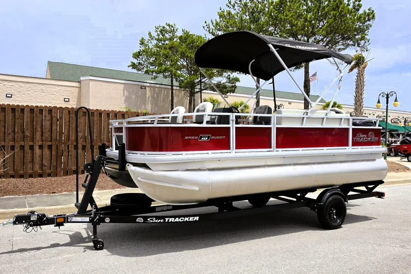 Slide: The Image of 2026 Sun Tracker Bass Buggy 18 DLX pontoon boat on trailer, parked outdoors. - 9