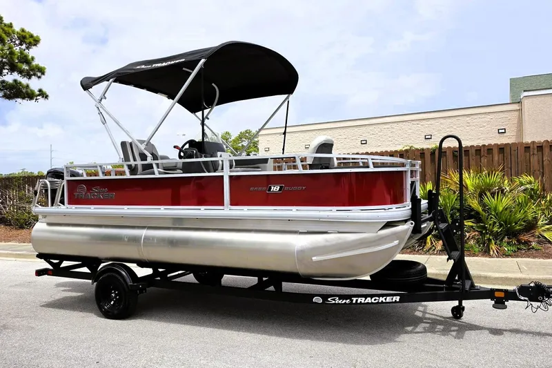 Slide: The Image of 2026 Sun Tracker Bass Buggy 18 DLX pontoon boat on trailer, parked outdoors. - 5