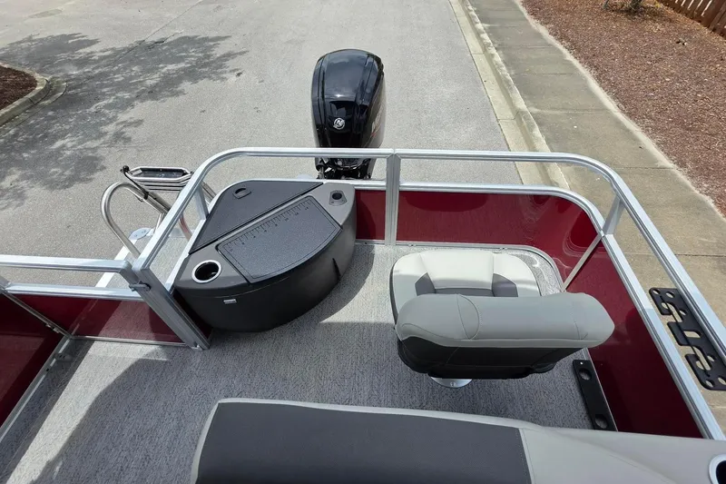 Slide: The Image of 2026 Sun Tracker Bass Buggy 18 DLX pontoon boat with seating and motor, parked on pavement. - 16