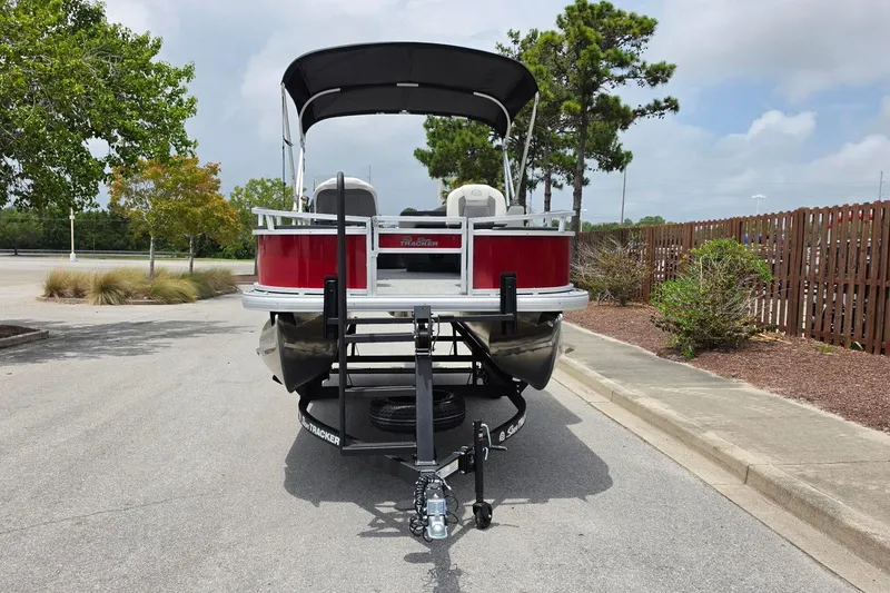 Slide: The Image of 2026 Sun Tracker Bass Buggy 18 DLX pontoon boat on trailer, parked outdoors. - 7