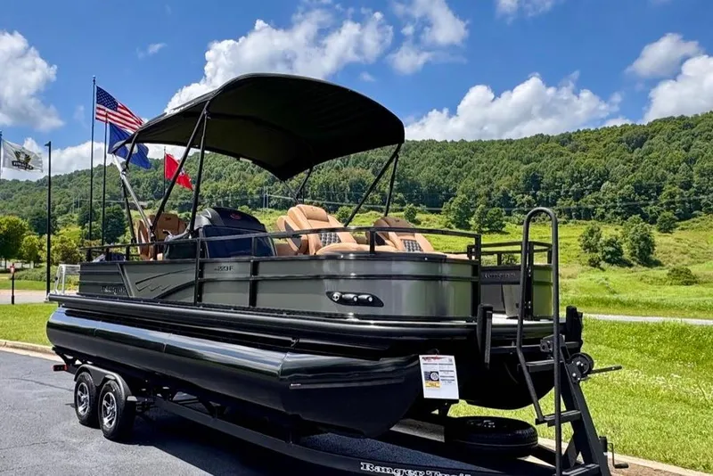 Slide: The Image of 2026 Ranger 223F pontoon boat on trailer, scenic background, flags waving, sunny day. - 1