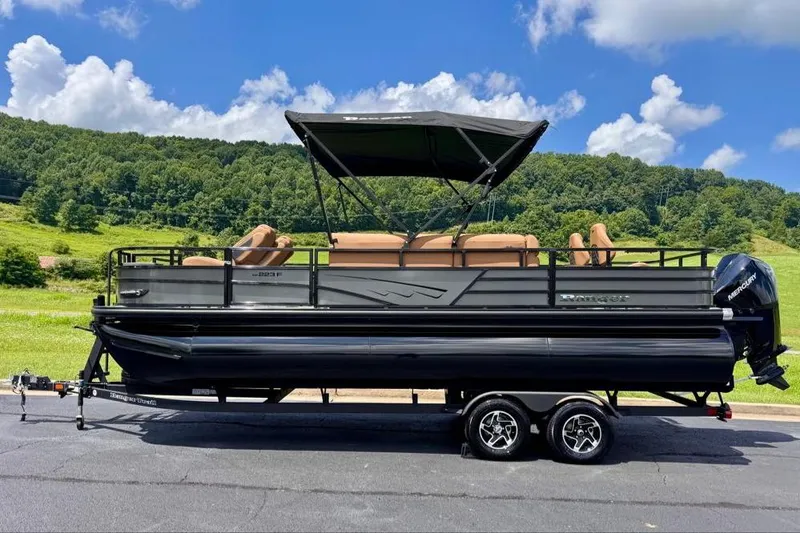 The Image of 2026 Ranger 223F pontoon boat with canopy, parked on trailer, scenic background. - 0
