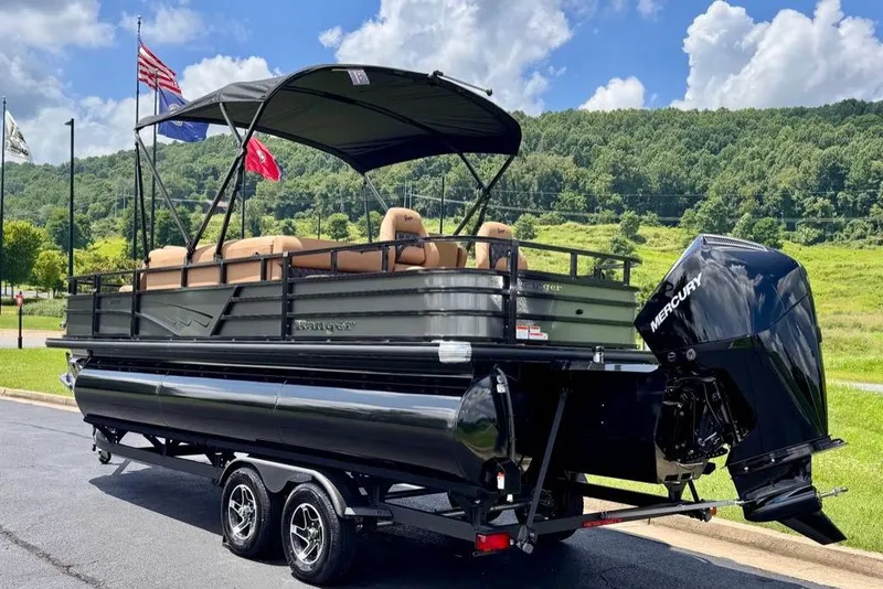 Slide: The Image of 2026 Ranger 223F pontoon boat with Mercury engine, parked on a trailer, scenic background. - 4