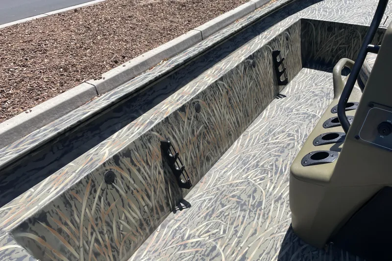 Slide: The Image of 2026 Tracker Grizzly 1860 CC boat interior with camouflage design and rod holders. - 14