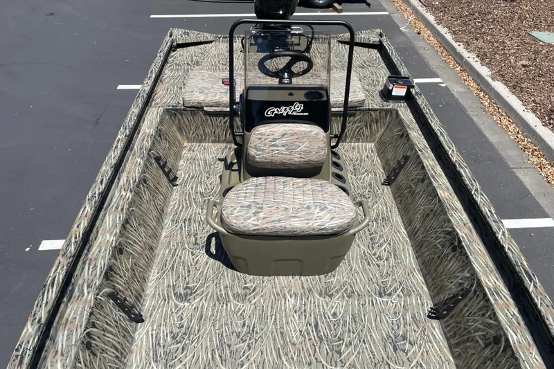 Slide: The Image of 2026 Tracker Grizzly 1860 CC boat with camouflage interior, parked on asphalt. - 10