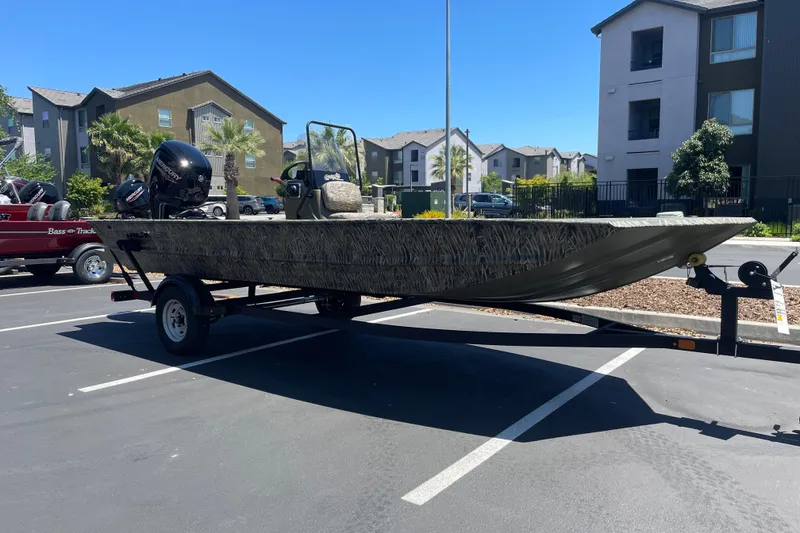 Slide: The Image of 2026 Tracker Grizzly 1860 CC boat on trailer in parking lot, surrounded by buildings. - 3