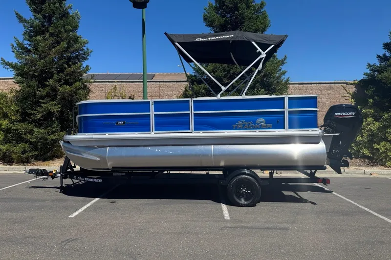 Slide: The Image of 2026 Sun Tracker Party Barge 18 DLX pontoon boat with Mercury engine in parking lot. - 2