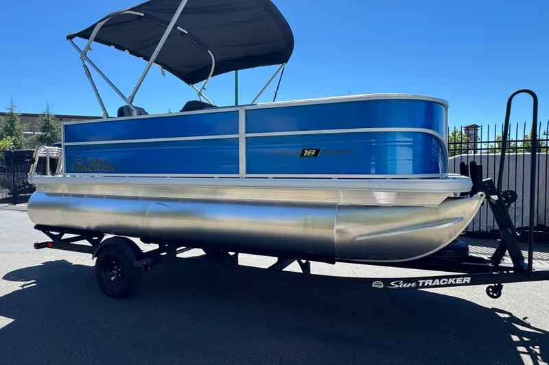 Slide: The Image of 2026 Sun Tracker Party Barge 18 DLX pontoon boat on trailer, blue and silver design. - 3
