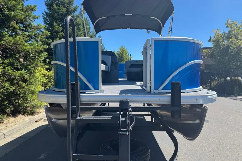 Slide: The Image of 2026 Sun Tracker Party Barge 18 DLX pontoon boat on trailer, blue exterior, sunny day. - 6